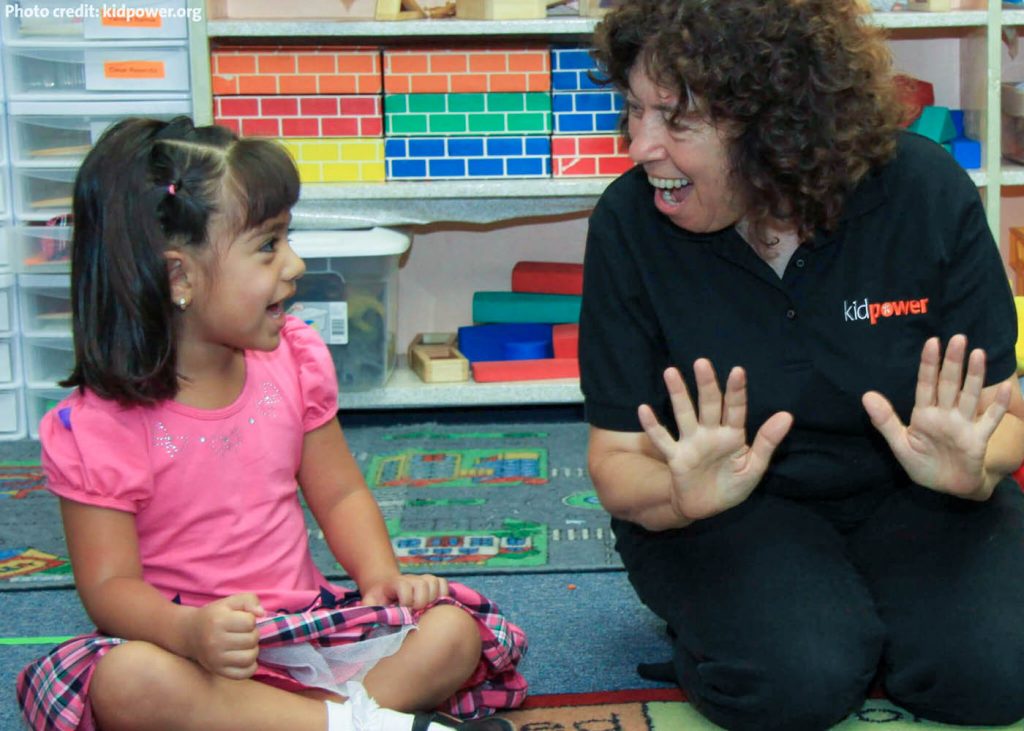 Irene van der Zande smiles as she works with a young child, who is also smiling.